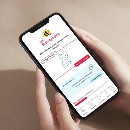 Personne tenant son smartphone. On peut y voir sur l'écran, le prototype d'une application mobile dédié à l'apprentissage du langage des signes.