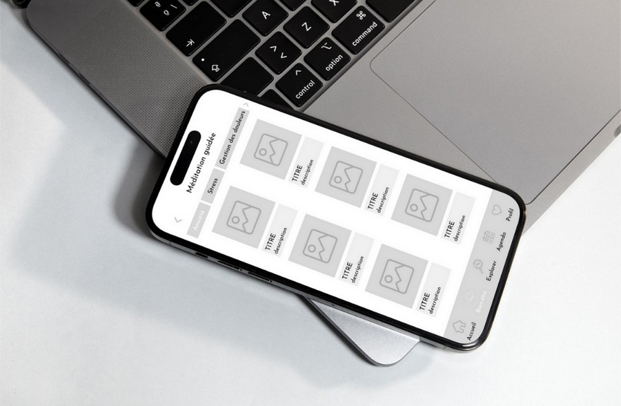 Smartphone posé près d'un ordinateur portable. On peut voir une page de wireframe en cours de création sur l'écran du smartphone.